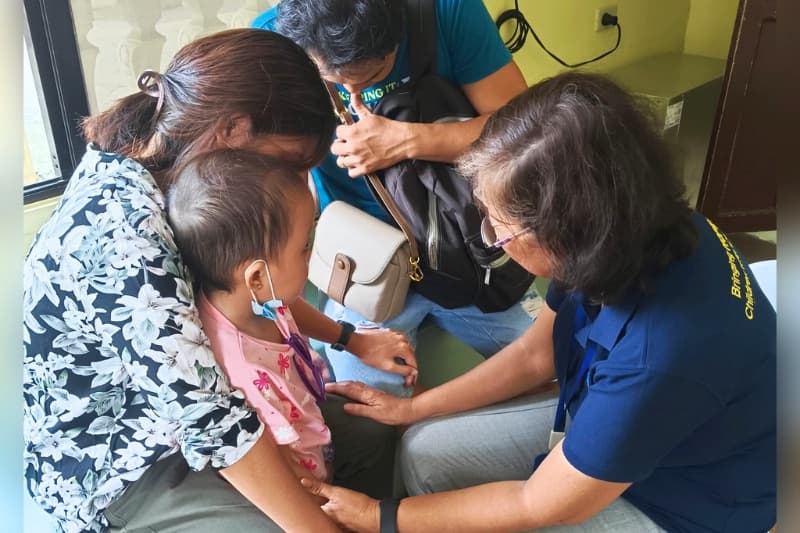 Everlasting Hope staff and a caregiver comfort a young child.