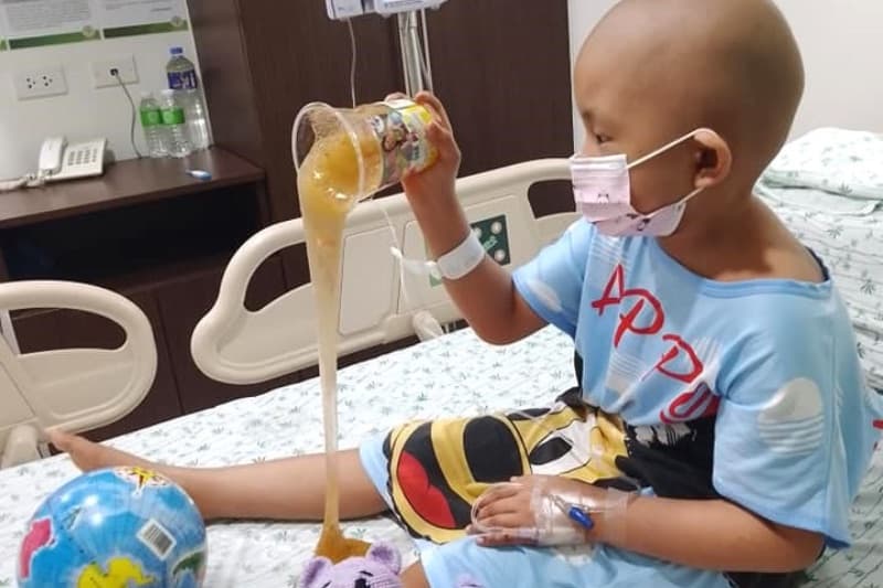 A child reads and plays while receiving treatment in a hospital room.